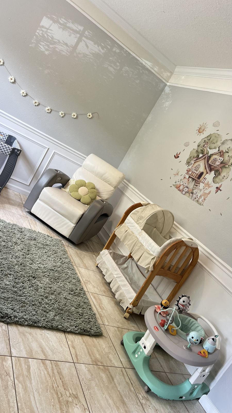 Quiet corner with a bassinet, glider chair, and soft green rug for naps